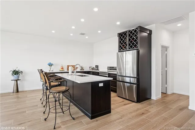 a kitchen with stainless steel appliances granite countertop a sink a stove a refrigerator and a refrigerator with wooden floor