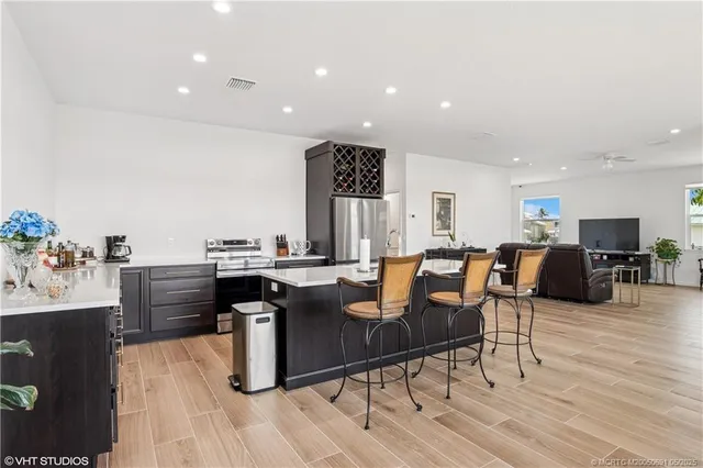 a living room with furniture a wooden floor and kitchen view