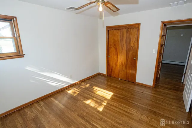 a view of empty room with wooden floor and fan