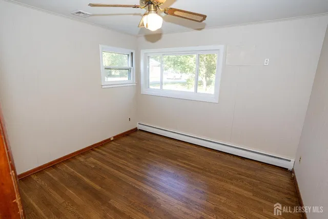 an empty room with wooden floor chandelier fan and windows