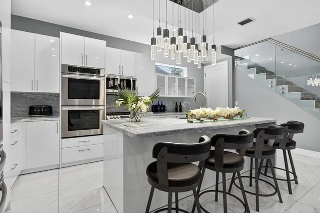 a kitchen with stainless steel appliances kitchen island granite countertop a dining table and chairs in it