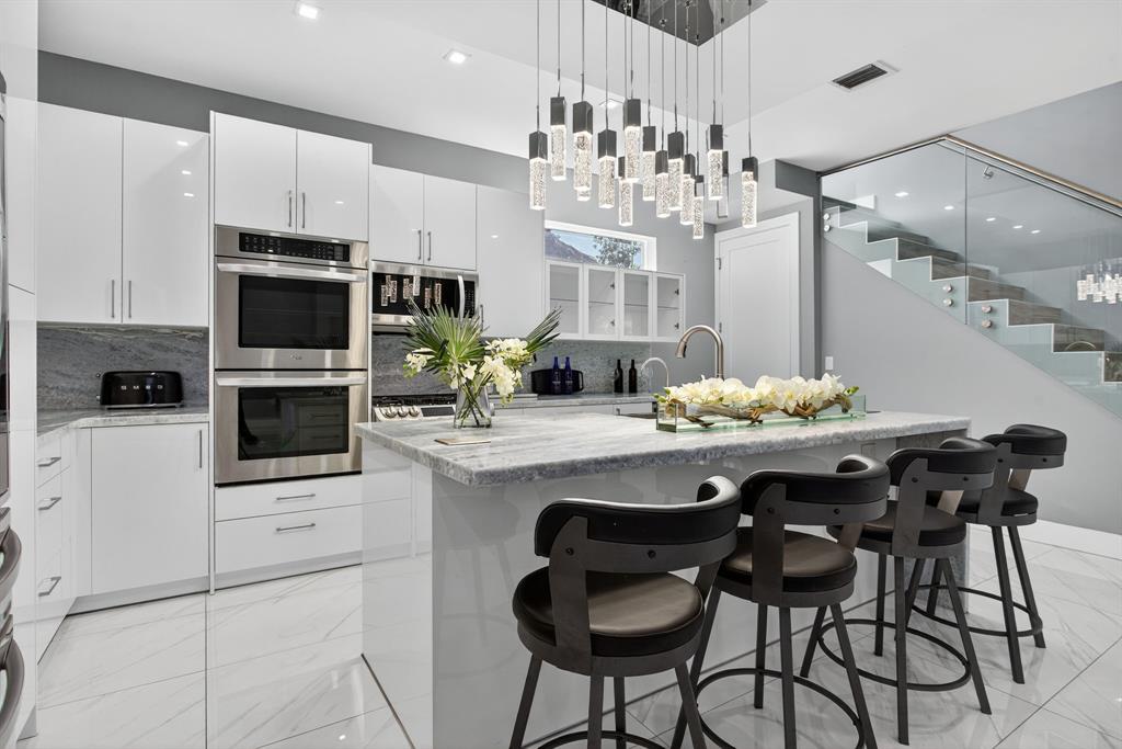 a kitchen with stainless steel appliances kitchen island granite countertop a dining table and chairs in it