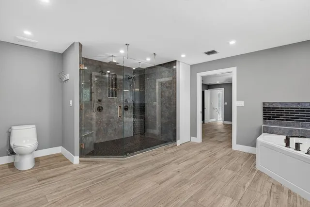 a bathroom with a sink a bathtub a mirror a vanity and shower