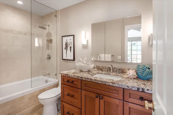 a bathroom with a granite countertop sink toilet mirror and bathtub