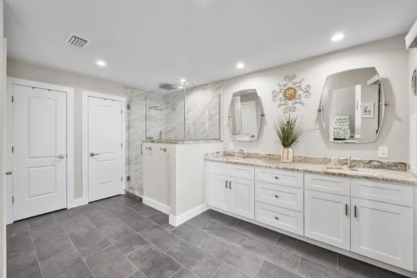 a spacious bathroom with a granite countertop sink a mirror and shower