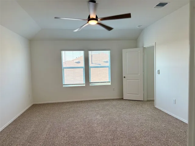 an empty room with chandelier fan and windows