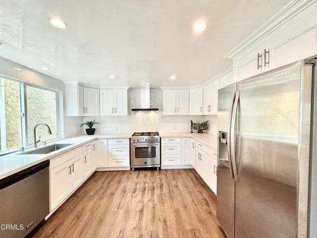 a large kitchen with a refrigerator a sink a stove a microwave and cabinets