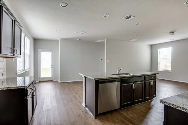 a kitchen with stainless steel appliances granite countertop a sink and wooden floor