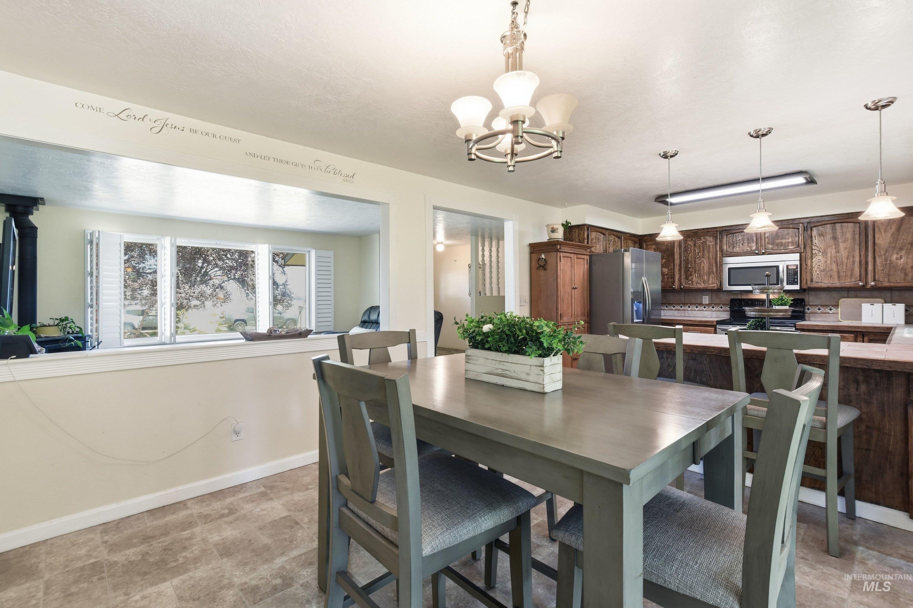 15095 David Street Caldwell, ID 83607 - Photo 12 of 39 Dining area featuring tile flooring, a chandelier, and a pass-through window with plantation shutters