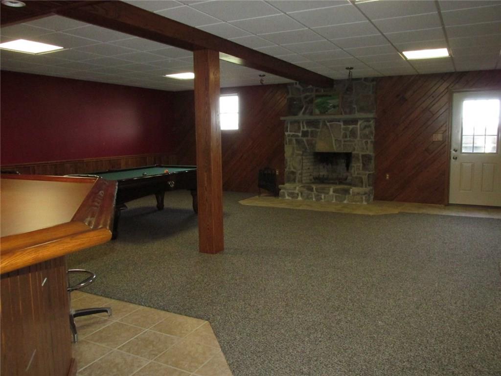 243 Baer Ridge Road Somerset, PA 15501 - Photo 16 of 25 Now we are on the lower lever with a wood burning fireplace. To the right is an outside door. Ceramic tile runs around the bar for easy clean up!