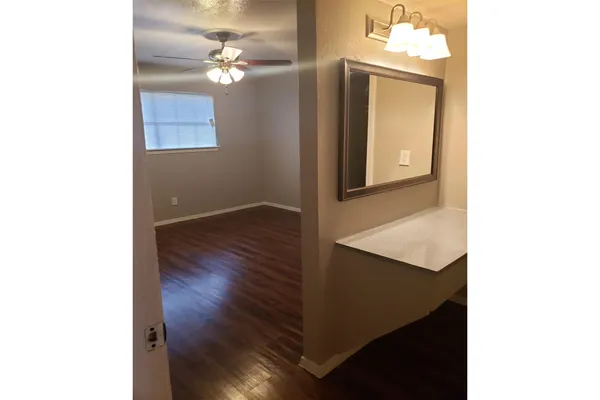 a view of a room with wooden floor and a ceiling fan