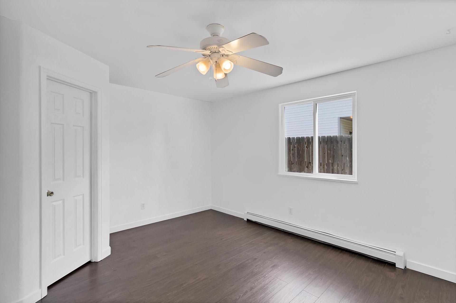 1124 Powell Street Fruita, CO 81521 - Photo 6 of 16 an empty room with wooden floor chandelier fan and windows