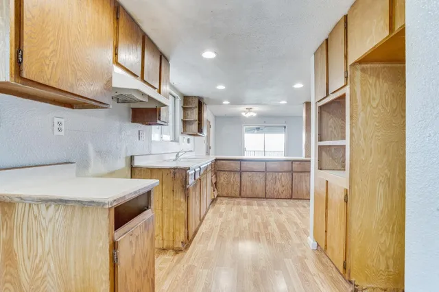 a kitchen with a refrigerator a sink and dishwasher with wooden floor