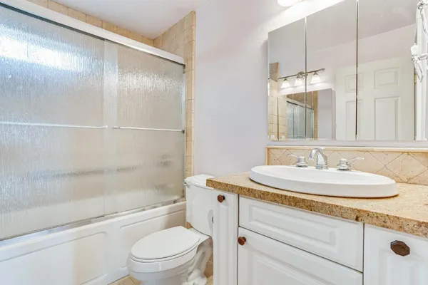 a bathroom with a granite countertop sink a toilet and shower