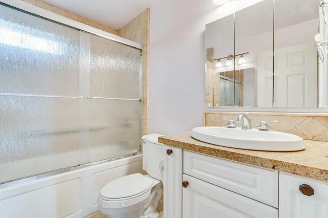 a bathroom with a granite countertop sink a toilet and shower