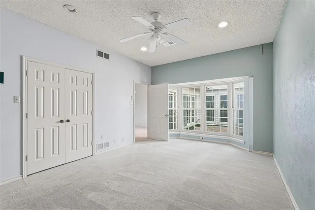 a view of an empty room with a window and a kitchen