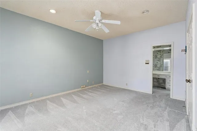 an empty room with a ceiling fan and closet area