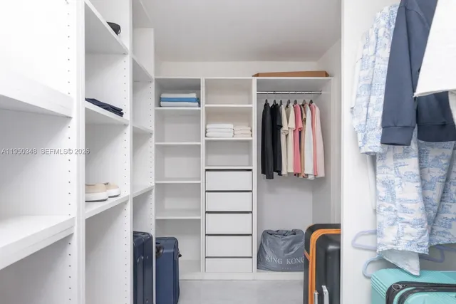 a view of walk in closet with clothes and shoes