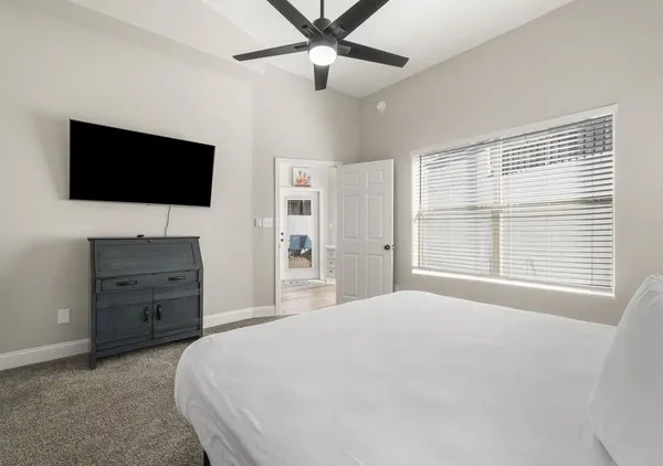 a spacious bedroom with a bed and a flat screen tv