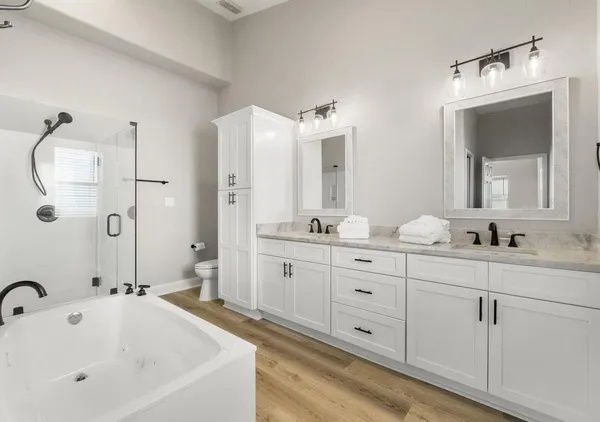 a bathroom with a double vanity sink mirror and bathtub