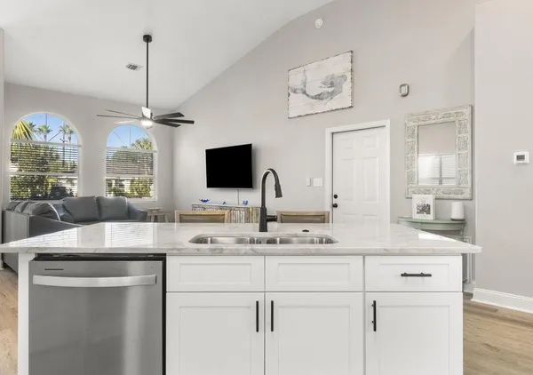 a room with kitchen island a sink and a flat screen tv