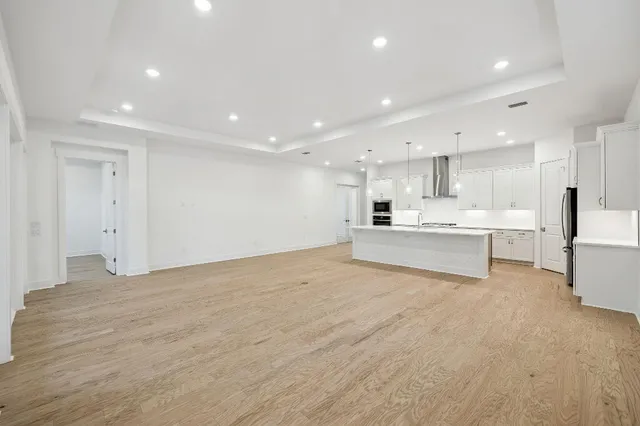 a large white kitchen with kitchen island a stove a sink and a refrigerator with white cabinets