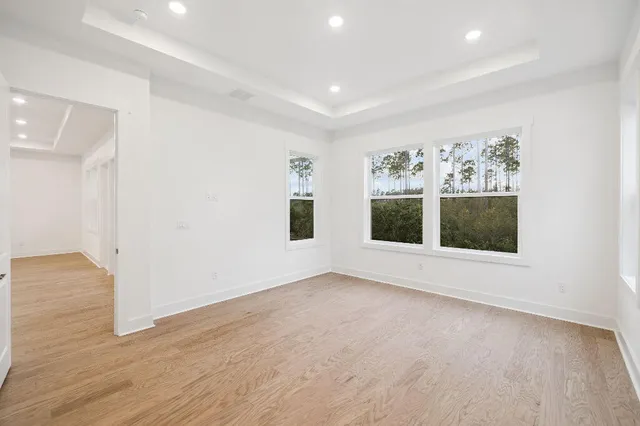 a view of an empty room with a window and hardwood floor