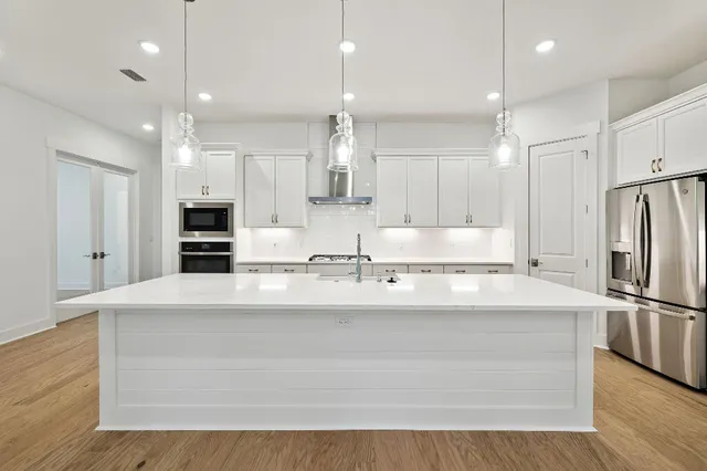 a large kitchen with kitchen island a stove a refrigerator and a sink with wooden floor