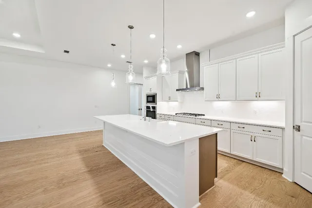 a large white kitchen with a sink a stove and dishwasher with wooden floor