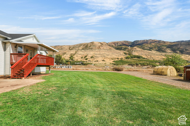 1045 West 3600th South Perry, UT 84302 - Photo 48 of 57 Expansive grassy area, wood-sided residence, red wood deck, covered porch, distant mountainous terrain