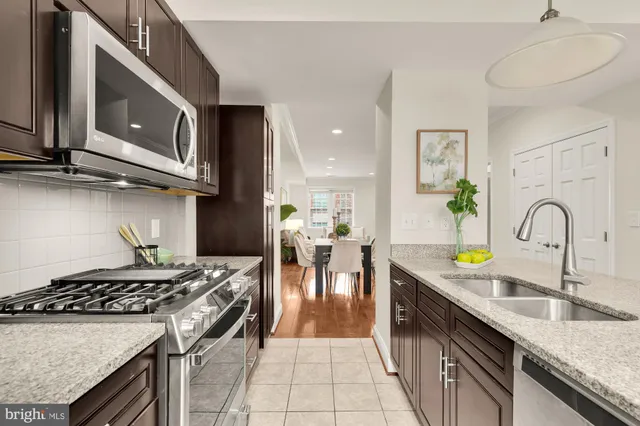 a kitchen with stainless steel appliances granite countertop a stove a sink and a microwave