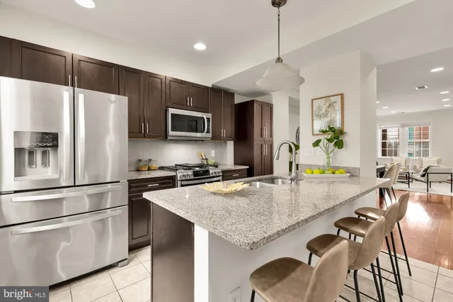 a kitchen with granite countertop a stove a refrigerator and a sink with cabinets