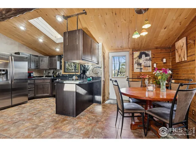 a kitchen with stainless steel appliances kitchen island granite countertop a table chairs and a refrigerator