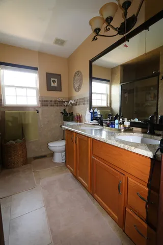 a spacious bathroom with a double vanity sink a mirror and a toilet