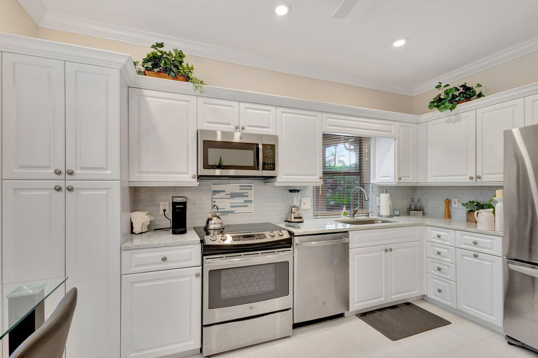 16151 West Bay Drive, Unit 161 Jupiter, FL 33477 - Photo 12 of 25 a kitchen with white cabinets stainless steel appliances and sink