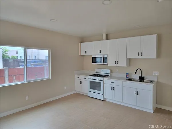 a kitchen with stainless steel appliances granite countertop a sink a stove a refrigerator and white cabinets