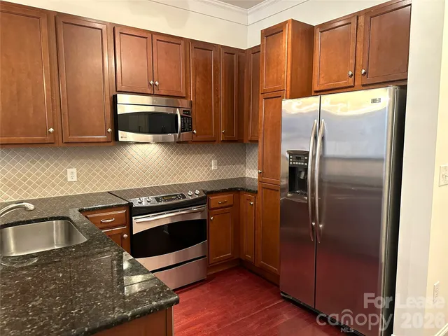 a kitchen with stainless steel appliances granite countertop a refrigerator a stove a sink and cabinets