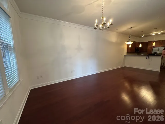an empty room with a chandelier fan and wooden floor