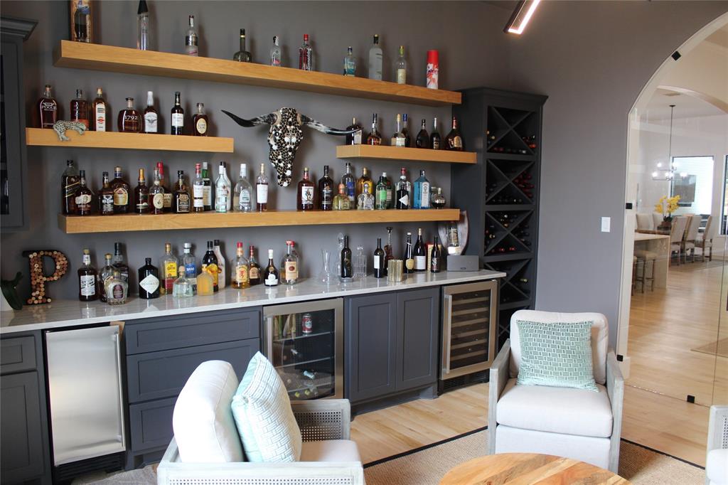 333 Renaissance Lane Heath, TX 75032 - Photo 19 of 35 Custom wet bar featuring a solid surface countertop, wood-finish floating shelves, under-counter refrigeration, and built-in wine storage