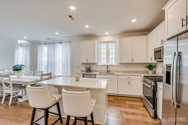 a large kitchen with stainless steel appliances a table chairs refrigerator and a sink