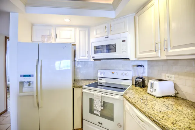 a view of a kitchen with kitchen island a sink stainless steel appliances cabinets and a counter top space