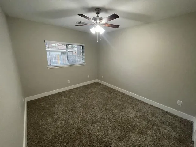 an empty room with a chandelier fan and windows