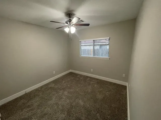 en empty room with windows and chandelier fan