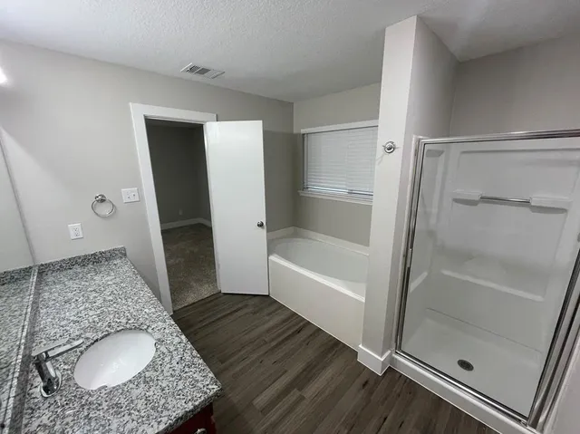 a bathroom with a granite countertop sink and a bathtub