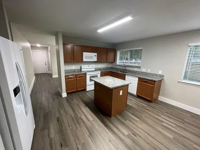 a large kitchen with wooden floors and stainless steel appliances