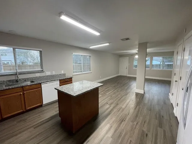 a kitchen with granite countertop a sink stove and wooden floor
