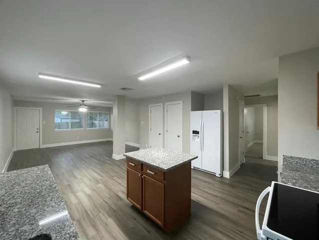 a living room with hard wood floors and a kitchen