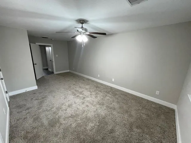 en empty room with windows and ceiling fan