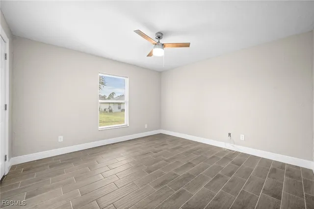 an empty room with a window and ceiling fan