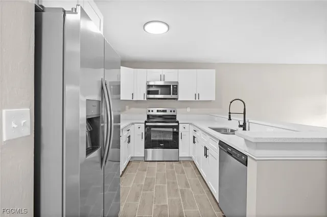 a kitchen with stainless steel appliances a refrigerator sink and white cabinets